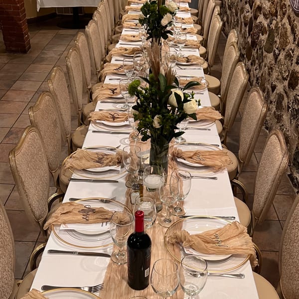 Long dining table set for a Pavesi Restaurant event with elegant place settings and floral centerpieces.