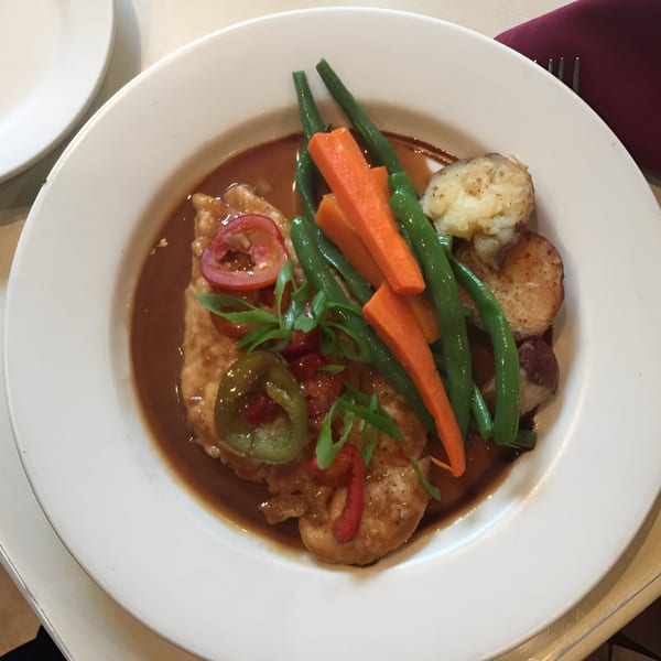 Pavesi Restaurant's chicken dish with green beans, carrots, and roasted potatoes in a rich sauce.