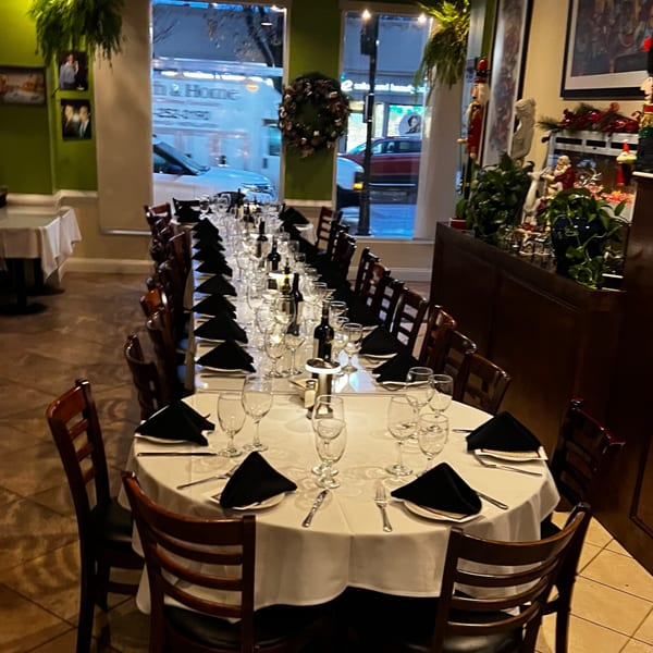 Long dining table set for a large party at Pavesi Restaurant, with wine bottles and glasses.